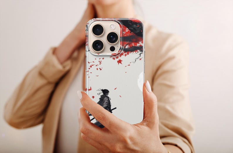 May include: A clear phone case featuring a Japanese-inspired design. The artwork depicts a samurai figure with a sword, set against a backdrop of red leaves and a full moon. The case is designed for a smartphone.