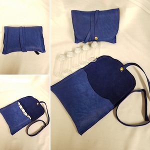 May include: A blue leather pouch with a flap closure and a strap. The pouch is open and contains several small glass vials. The pouch is on a white surface.