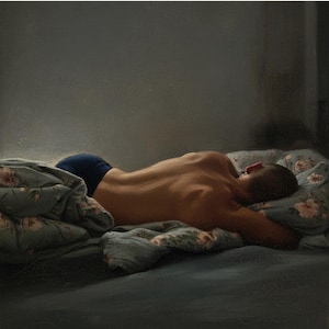 May include: A person lies face down on a bed, wearing dark blue underwear. The bed has a floral patterned pillow and a floral patterned blanket. The scene is dimly lit, with a focus on the person's back.