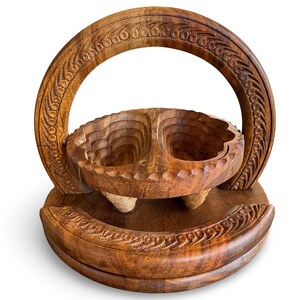 Peut inclure: Un panier &agrave; fruits en bois sculpt&eacute;. Le panier est dot&eacute; d'une anse et d'un bol divis&eacute;, soutenu par trois petits pieds. Le bois a une teinte naturelle et chaleureuse, et le design comprend des sculptures complexes.