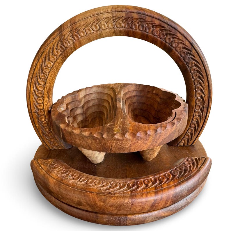 Peut inclure: Un panier &agrave; fruits en bois sculpt&eacute;. Le panier est dot&eacute; d'une anse et d'un bol divis&eacute;, soutenu par trois petits pieds. Le bois a une teinte naturelle et chaleureuse, et le design comprend des sculptures complexes.