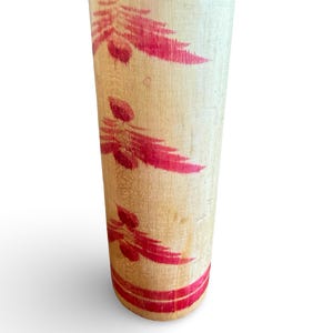 Peut inclure: Un rouleau &agrave; p&acirc;tisserie cylindrique en bois avec une finition naturelle couleur beige clair. La surface est orn&eacute;e de trois motifs de feuilles rouges en forme de foug&egrave;re dispos&eacute;s verticalement, avec deux bandes rouges horizontales &agrave; la base.
