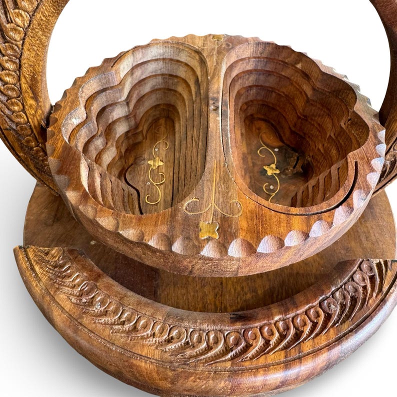 Peut inclure: Un panier &agrave; fruits en bois fait &agrave; la main avec un design unique en couches. Le panier pr&eacute;sente des sculptures complexes et des accents dor&eacute;s d&eacute;coratifs. Les poign&eacute;es et la base sont &eacute;galement sculpt&eacute;es avec des motifs d&eacute;taill&eacute;s.