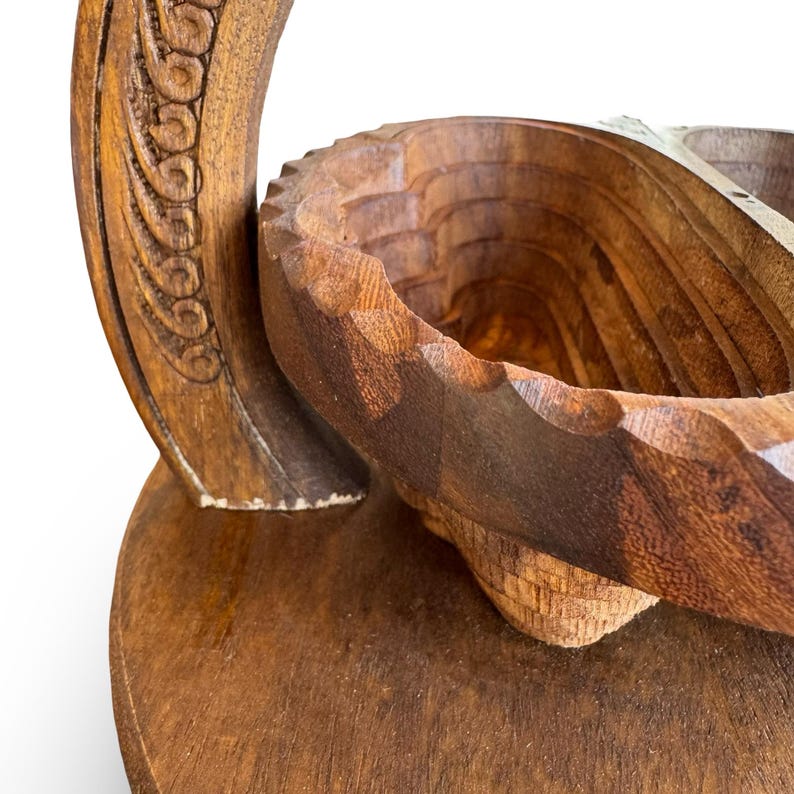 Peut inclure: Un panier &agrave; fruits en bois fait &agrave; la main avec une poign&eacute;e sculpt&eacute;e et une base ronde. Le panier a une finition en bois naturel et un design unique en couches. La poign&eacute;e pr&eacute;sente des d&eacute;tails sculpt&eacute;s complexes.