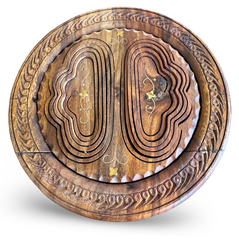 Peut inclure: Un panier &agrave; fruits rond en bois, pliable. Le bois brun fonc&eacute; pr&eacute;sente des sculptures complexes sur le bord et &agrave; l'int&eacute;rieur. Des accents dor&eacute;s sont int&eacute;gr&eacute;s au design, ajoutant une touche d'&eacute;l&eacute;gance.