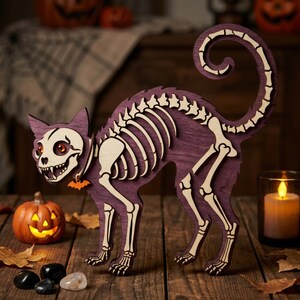 May include: A purple wooden cat silhouette featuring a cream-coloured skeletal overlay. The cat has an arched back, a curled tail, and a small orange bat-shaped charm hanging from its neck. The skeletal design includes a detailed skull and ribs.