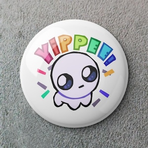 Peut inclure: Bouton blanc avec un personnage de dessin animé en forme de fantôme et le mot "YIPPEE" en couleurs arc-en-ciel. Le personnage a de grands yeux et un contour violet. Des formes colorées en forme de confettis entourent le personnage.