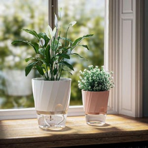 Peut inclure: Deux pots de fleurs auto-arrosants sur un rebord de fenêtre en bois. Le grand pot blanc a un design en spirale et contient un spathiphyllum. Le petit pot rose contient une petite plante verte. Les deux ont des bases transparentes.