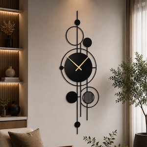 Op de afbeelding: Een verticale wandklok met een zwarte ronde wijzerplaat en gouden wijzers, omringd door een geometrische compositie van zwarte metalen cirkels, verticale lijnen en massieve zwarte schijven in een langwerpig en gelaagd ontwerp.