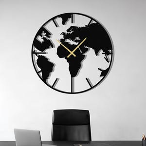 May include: A black and gold world map wall clock with gold hands hangs on a white wall. The clock is above a black desk with a laptop, pen holder, and a black leather chair. The room has a large window with a city view.