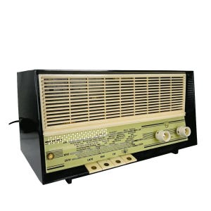 Può includere: Radio vintage nera e color crema con una griglia per altoparlanti orizzontale. La radio ha un pannello verde chiaro con manopole bianche. Le lettere MW, UKW e LW sono visibili sul davanti.