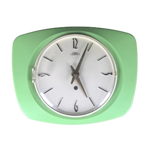 May include: A vintage green Prim clock with a white face. The clock has black numerals and hands, and a silver-colored frame. The clock is a retro design, with a rectangular shape and rounded corners.