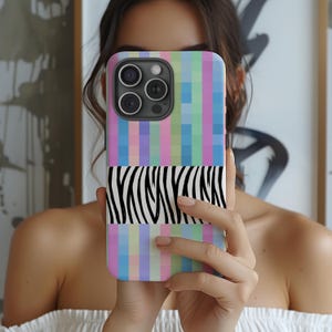 May include: A smartphone case featuring a colorful pixelated design in pastel hues of pink, blue, green, and purple. The case also has a horizontal zebra stripe pattern in black and white.
