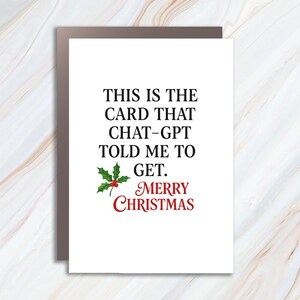 May include: A white Christmas card with a brown border. The card has black text that reads "THIS IS THE CARD THAT CHAT-GPT TOLD ME TO GET. MERRY CHRISTMAS." A sprig of holly with red berries is also on the card.
