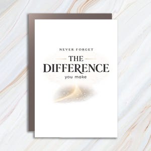 May include: A white rectangular greeting card featuring the black text NEVER FORGET THE DIFFERENCE you make centered on the front. Below the text is a soft, glowing golden light effect with small sparkling particles against a white background.