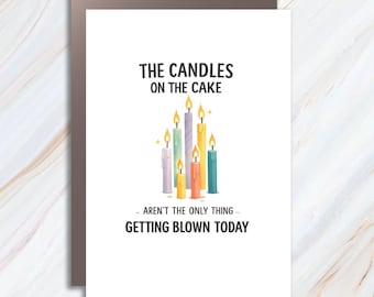 May include: A white greeting card featuring a cluster of seven colorful lit candles in the center. The text above reads THE CANDLES ON THE CAKE and the text below reads - AREN'T THE ONLY THING - GETTING BLOWN TODAY in bold black lettering.