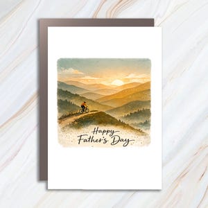 May include: A Father's Day card featuring a watercolor painting of a cyclist riding through a mountain landscape at sunset. The card has the text "Happy Father's Day" in a handwritten style.