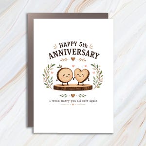 May include: A white greeting card featuring the text HAPPY 5TH ANNIVERSARY and i wood marry you all over again. The illustration shows a circular wood slice character and a heart-shaped wood slice character holding hands on a log base.