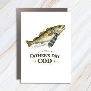 Może przedstawiać: Karta na Dzień Ojca z akwarelową ilustracją dorsza w niebieskim paskowanym krawacie. Na karcie napisano "Got you a Father's Day Cod" zabawną czcionką, z rozbłyskami gwiazd. Karta jest na białym tle.