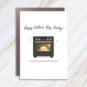 May include: A Father's Day card with a black oven illustration. The oven door is open, revealing a smiling bun. The text reads "Happy Father's Day, Daddy!" and "FROM YOUR LITTLE BUN IN THE OVEN."