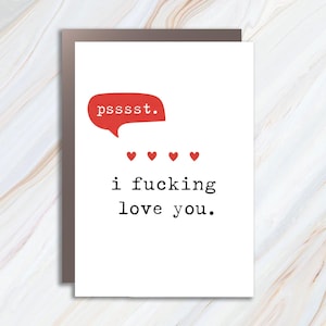 May include: A white greeting card featuring a red speech bubble with the text psssst. Below the speech bubble are four small red hearts arranged in a horizontal row. The text i fucking love you. is printed in black typewriter-style font.