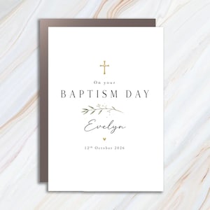 Può includere: Un biglietto d'invito per battesimo rettangolare bianco con un'icona a croce dorata in alto, il testo On your BAPTISM DAY, un'illustrazione di un rametto botanico verde, il nome Evelyn in corsivo, un piccolo cuore dorato e la data 12th October 2026.