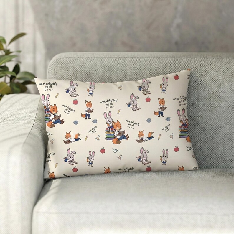May include: Rectangular pillow with a repeating pattern of cartoon foxes and rabbits reading books, with apples and pencils scattered across a cream background. The text "most definitely not all in a row" is also present.