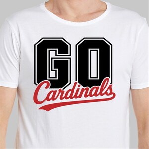 May include: White t-shirt with the words "GO Cardinals" in black and red lettering. The word "GO" is in a bold, blocky font with a black outline. The word "Cardinals" is in a cursive font.