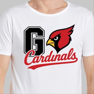 May include: White t-shirt featuring a graphic design with the text "Go Cardinals". The design includes a large black "G" with a white outline, a red cardinal bird, and the word "Cardinals" in red script.