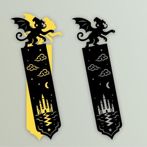 May include: Two decorative bookmarks. Each features a black silhouette of a winged monkey. The bookmarks have a black rectangle design with a night sky theme. One has a yellow backing, the other is solid black. The design includes clouds, stars, a crescent moon, and a castle.