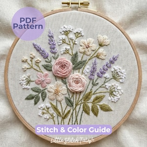 May include: An embroidered floral design in a wooden hoop. The design features pink roses, lavender, and cream-colored flowers with green leaves. Text includes "PDF Pattern" and "Stitch & Color Guide".