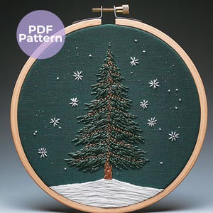 Pode incluir: Arte de bordado costurada à mão em um bastidor de madeira. Uma árvore de Natal verde está centrada em um tecido verde escuro, com flocos de neve brancos e um chão coberto de neve. O texto "PDF Pattern" está em um círculo roxo.