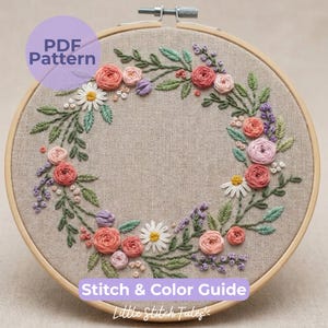 May include: An embroidered floral wreath in a wooden hoop. The wreath features pink, peach, and purple flowers, green leaves, and white daisies. The text "PDF Pattern" and "Stitch & Color Guide" are visible. The words "Little Stitch Tales" are also visible.