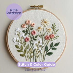 Peut inclure: Un tambour à broder circulaire en bois contenant un panneau en tissu avec un motif floral. La broderie présente des roses roses, des marguerites blanches et de petites fleurs blanches avec des feuilles et des tiges vertes. Le texte indique PDF Pattern.