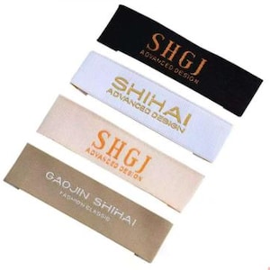 May include: Four rectangular fabric labels in black, white, beige, and tan. Each label features text in a contrasting color. The labels read "SHGJ ADVANCED DESIGN", "SHIHAI ADVANCED DESIGN", "SHGJ ADVANCED DESIGN", and "GAOJIN SHIHAI FASHION CLASSIC".