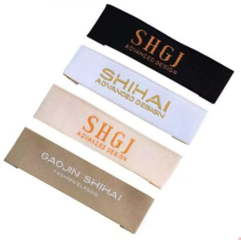 May include: Four rectangular fabric labels in black, white, beige, and tan. Each label features text in a contrasting color. The labels read "SHGJ ADVANCED DESIGN", "SHIHAI ADVANCED DESIGN", "SHGJ ADVANCED DESIGN", and "GAOJIN SHIHAI FASHION CLASSIC".