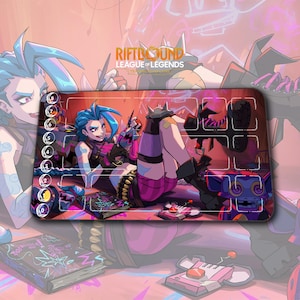 May include: A rectangular gaming mousepad featuring a colorful illustration of a character from League of Legends. The design includes a character with blue hair, a purple robot, and the text "RIFTBOUND LEAGUE OF LEGENDS".