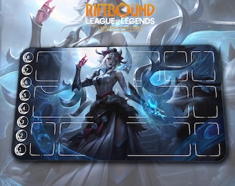 May include: A rectangular Riftbound League of Legends playmat featuring a detailed illustration of a female character in a dark outfit with blue and white accents. The mat has numbered zones and the game's logo.
