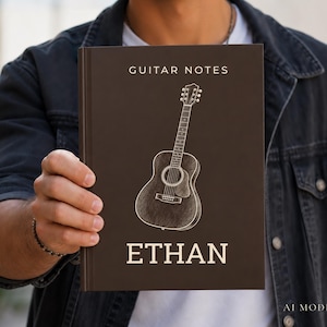 May include: A dark brown hardcover notebook titled GUITAR NOTES with a white line drawing of an acoustic guitar centered on the front cover. The name ETHAN is printed in white capital letters at the bottom of the cover in a clean sans-serif font.