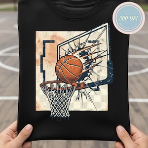 Op de afbeelding: Zwart T-shirt met een verweerde afbeelding van een basketbal die door een hoepel gaat, met een gebroken bord effect. De basketbal is oranje en bruin. Het ontwerp heeft een vintage, retro stijl.