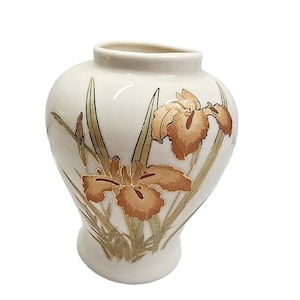 May include: Cream-colored ceramic vase with a bulbous body and a slightly flared rim. The vase is decorated with a detailed illustration of brown irises and green leaves. The design is accented with gold-colored lines.