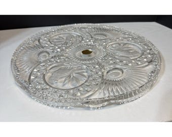 May include: A clear, round, glass serving platter with multiple compartments. The platter features intricate etched designs, including floral and geometric patterns. The edges are detailed with a diamond-cut pattern, adding to its elegant appearance.