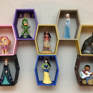 May include: A collection of colorful hexagonal shelves displaying various figurines. The shelves are painted in pink, purple, black, yellow, and blue. The figurines include characters from popular animated movies and TV shows.
