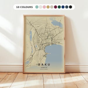 May include: A framed print of a map of Baku, Azerbaijan, in neutral tones. The map shows a detailed street layout, with a light blue coastal area and the city's name at the bottom. The frame is light wood, and the text "10 COLOURS" is at the top.