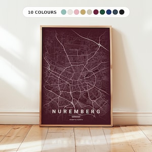 May include: A framed print of a map of Nuremberg, Germany, in a deep burgundy hue. The city's road network is shown in white, with the city name and coordinates at the bottom. The frame is light wood, and the print is displayed on a white wall.