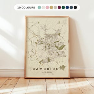 Op de afbeelding: Ingelijste kaartprint van Cambridge, Verenigd Koninkrijk, in een neutraal kleurenpalet. De kaart toont de stadsindeling met wegen en groene ruimtes. De tekst "CAMBRIDGE" staat gecentreerd onderaan.