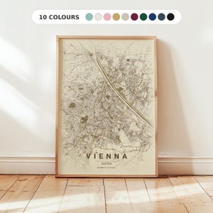 Op de afbeelding: Een ingelijste kaartprint van Wenen, Oostenrijk, in sepia tinten. De stadskaart is gedetailleerd, met straten en bezienswaardigheden zichtbaar. De tekst "VIENNA" staat onderaan, met het land en de coördinaten eronder. De lijst is van licht hout.