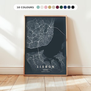 May include: A framed map print of Lisbon, Portugal, in a dark blue color scheme. The city's layout is depicted with white lines, and the text "LISBON" is prominently displayed. The print is encased in a wooden frame and is displayed against a white wall.