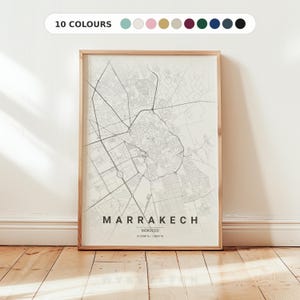 May include: A vertical framed map print of Marrakech, Morocco, featuring a light cream background with dark gray street lines. The text reads MARRAKECH, MOROCCO, and includes coordinates. A color palette bar at the top displays 10 circular swatches.