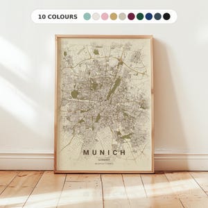Puede incluir: Una impresión enmarcada de un mapa de Múnich, Alemania, en una paleta de colores neutros. El mapa detalla el diseño de la ciudad, con el nombre de la ciudad y las coordenadas en la parte inferior. El texto "10 COLORES" está en la parte superior.